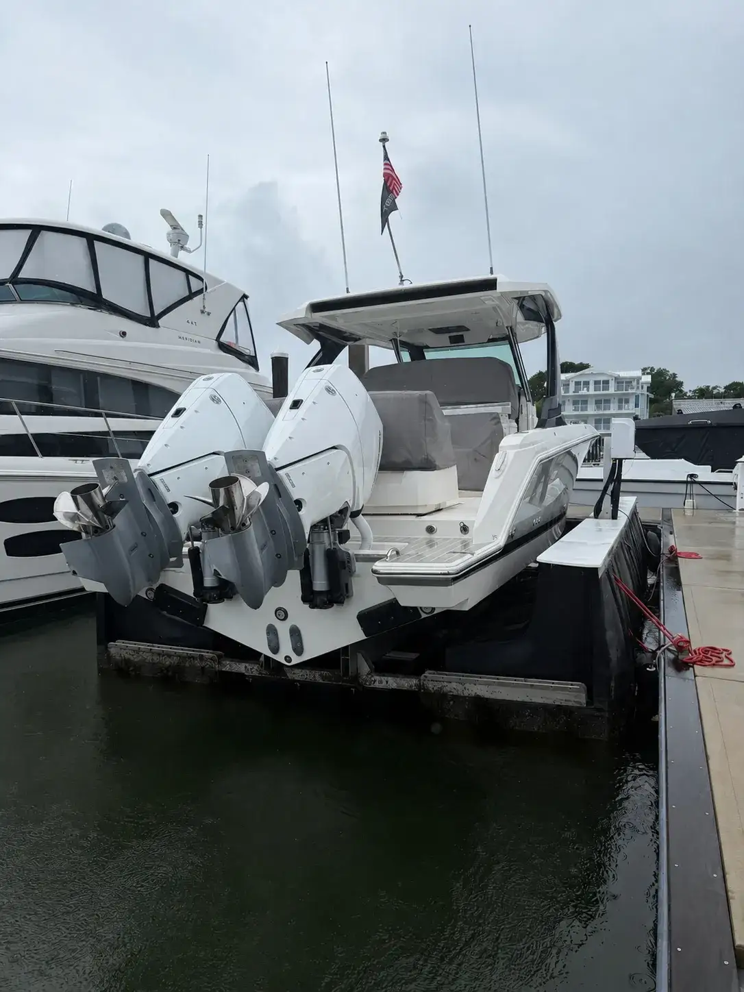 Twin outboard boat sitting on a floating boat lift in a marina slip